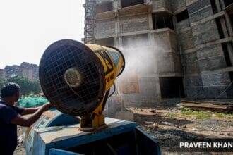 Workers use a Smog Gun to control dust at a construction site in New Delhi. (Express photo by Praveen Khanna)