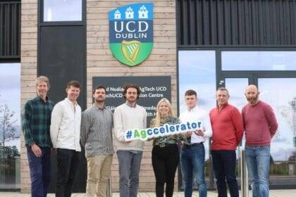 Eight people – seven men and one woman – stand in a line smiling in front of an AgTech UCD building. They are holding a sign that says #Agccelerator.